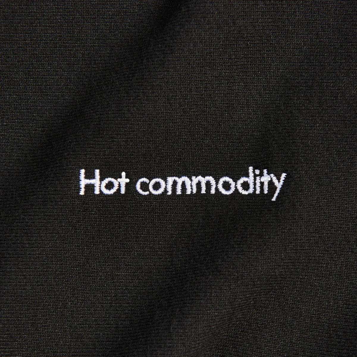 A black crewneck sweater with the words “Hot commodity” written on its chest.