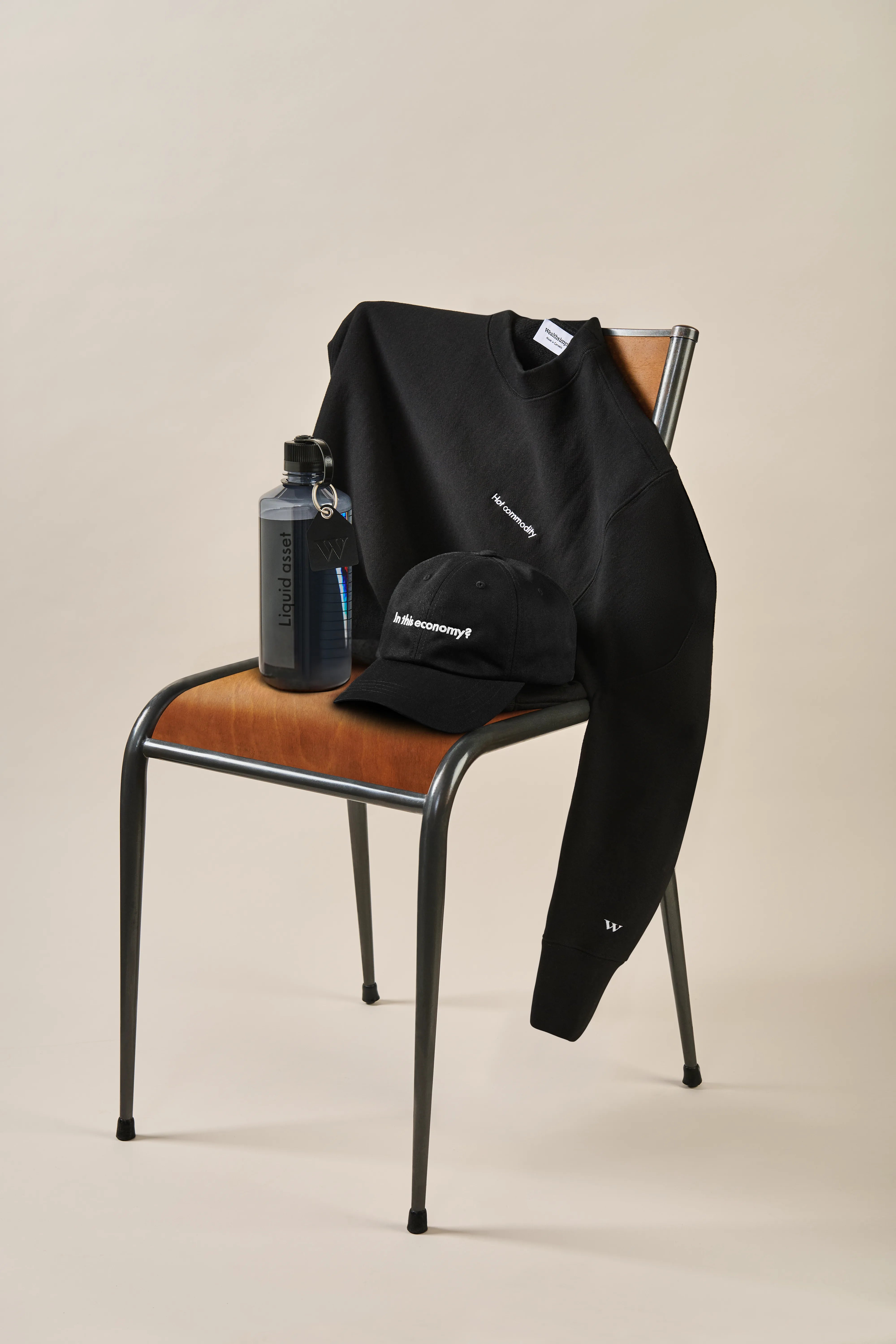 A Wealthsimple tote bag placed on a green chair. It&rsquo;s filled with a branded water bottle, a cap, and a laptop.